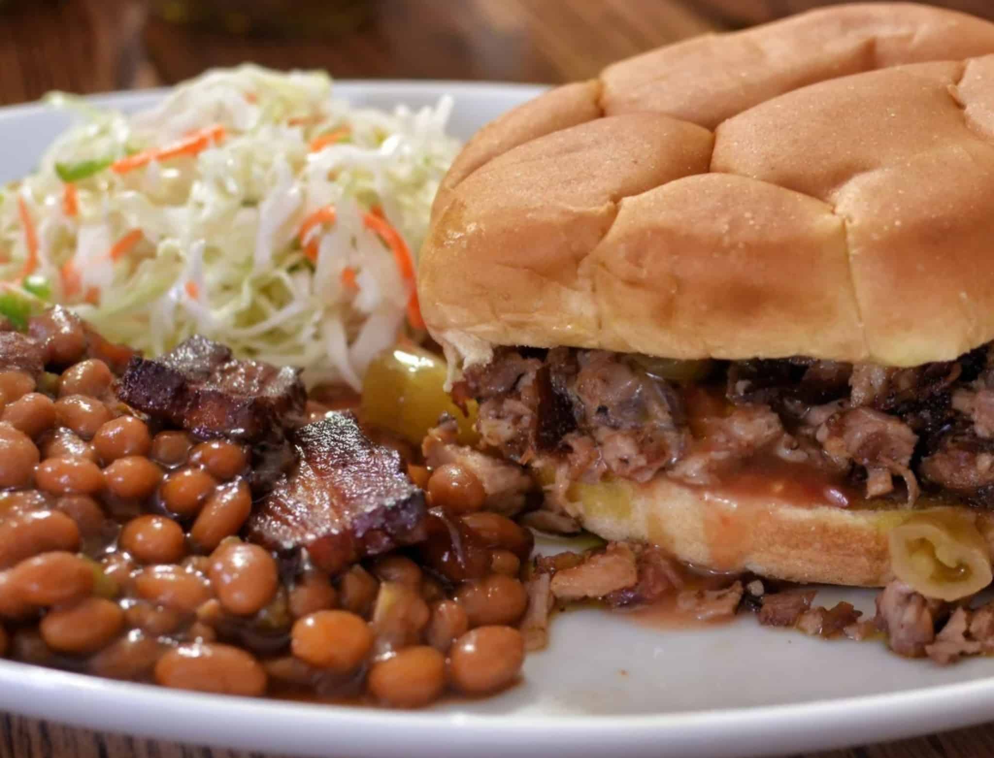 BBQ sandwich with coleslaw and baked beans, featuring Schmoka Boyz BBQ sauce.